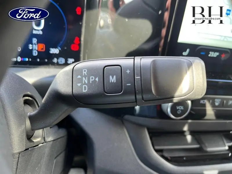 Gros plan sur la commande de boîte automatique avec levier multifonction dans l'habitacle du Ford Transit Custom gris.