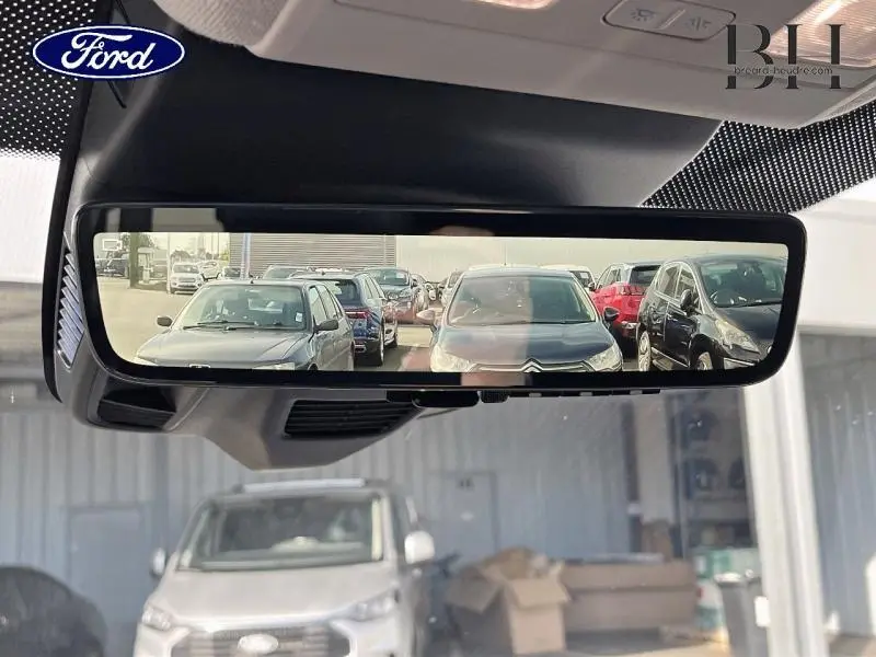 Vue du rétroviseur intérieur montrant la caméra de recul du Ford Transit Custom gris Magnetic métallisé en stationnement.