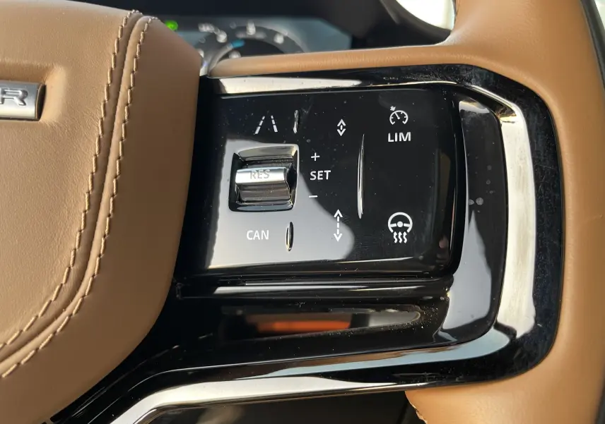 Gros plan sur les commandes de régulateur de vitesse sur le volant en cuir brun du Range Rover Sport 2023.