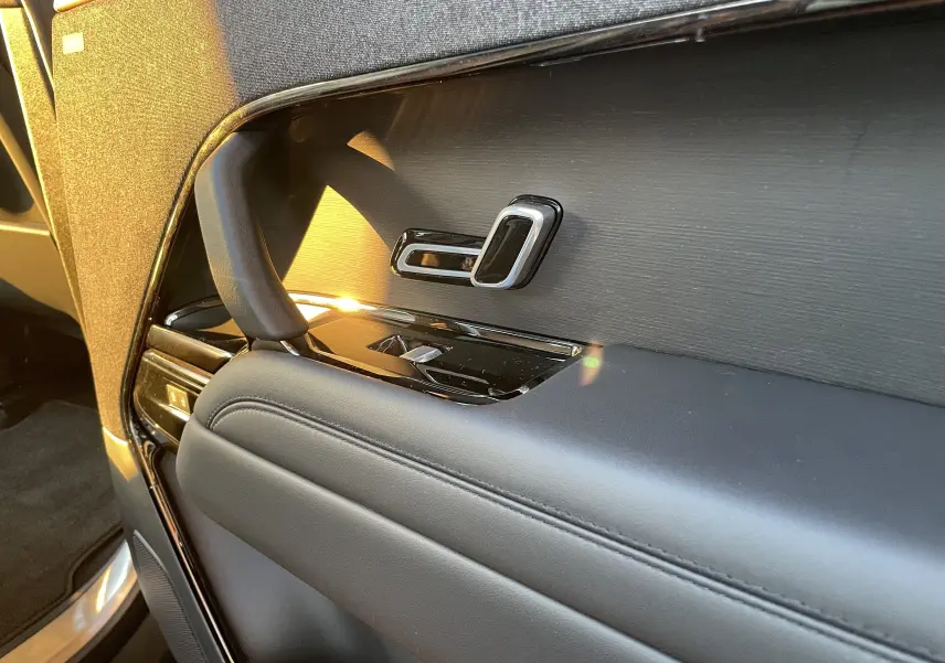 Détail de la porte intérieure côté gauche du Range Rover Sport 2023 en Carpathian Grey, avec commandes de siège et finition noire élégante.