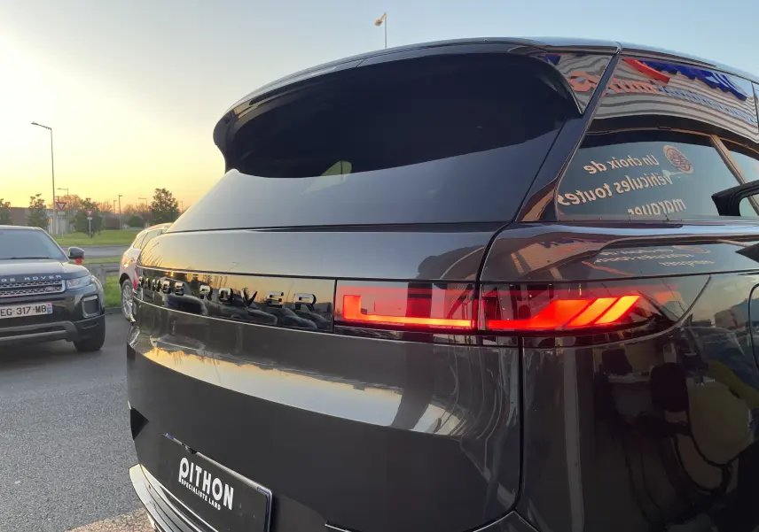 Vue 3/4 arrière d’un Range Rover Sport P440 HSE R-Dynamic Carpathian Grey avec feux arrière LED allumés.