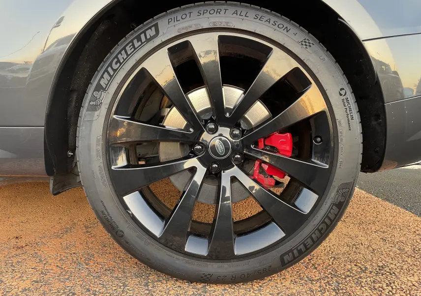 Gros plan sur la jante noire brillante 23'' avec étrier de frein rouge du Range Rover Sport Carpathian Grey 2023.