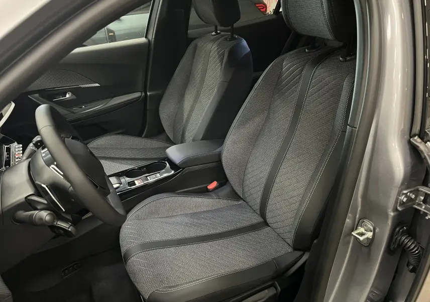 Vue intérieure côté conducteur du Peugeot 2008 gris Artense, mettant en valeur les sièges tissu et cuir noir au design moderne.