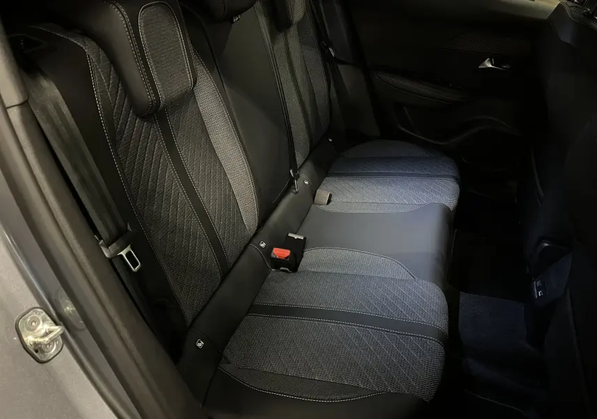 Vue intérieure côté arrière droit du Peugeot 2008 1.2 Hybrid 145ch, sièges en tissu et cuir noir avec surpiqûres blanches.