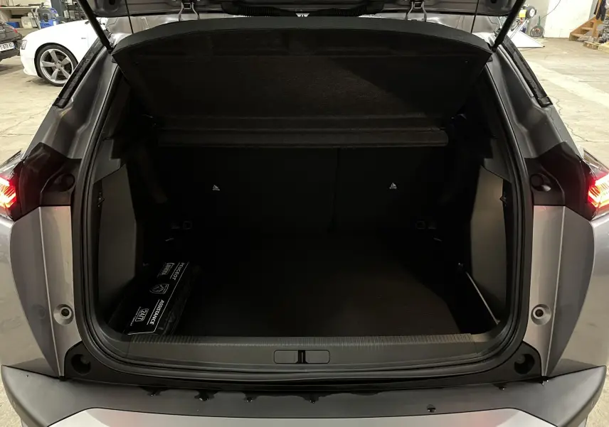 Coffre ouvert vu de l'arrière d'un Peugeot 2008 gris Artense Métal, avec espace de chargement vide et trousse d'assistance.