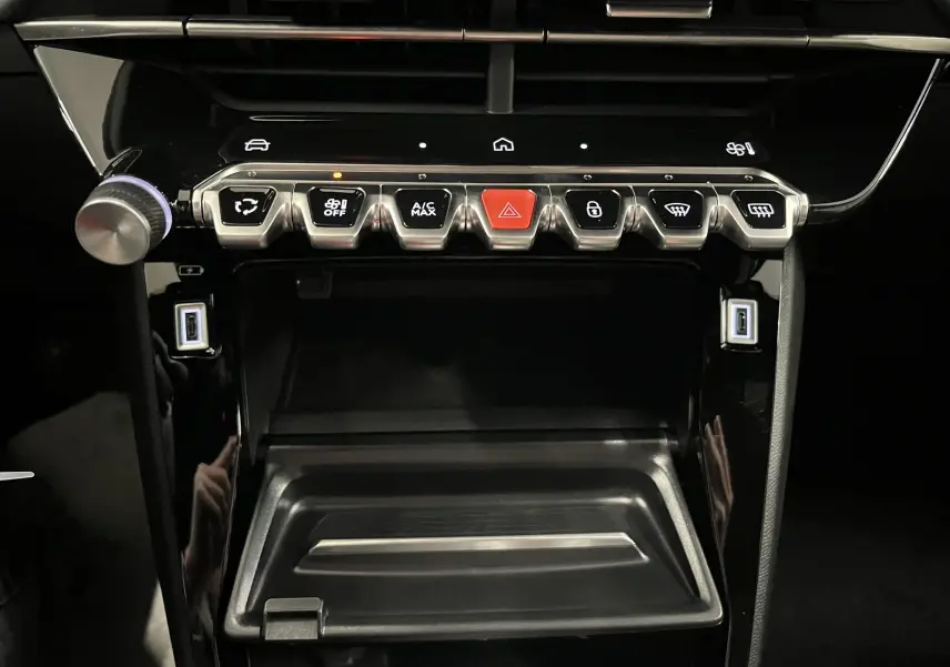 Vue rapprochée de la console centrale noire brillante du Peugeot 2008 1.2 Hybrid 145ch avec boutons de commande et ports USB.