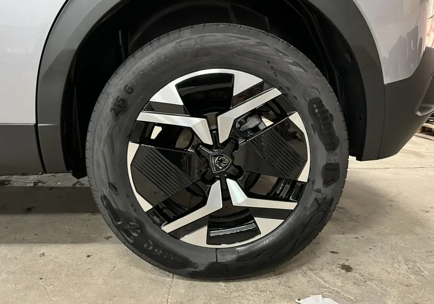 Gros plan sur la roue avant droite du Peugeot 2008 gris Artense Métal, avec jante bi-ton noire et argentée au design moderne.