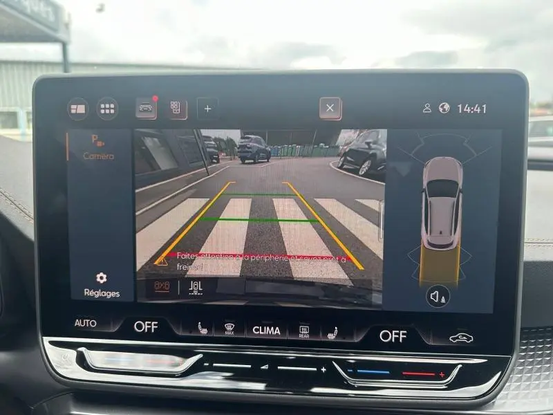 Écran tactile intérieur montrant la caméra de recul avec vue arrière sur un parking, tableau de bord noir.