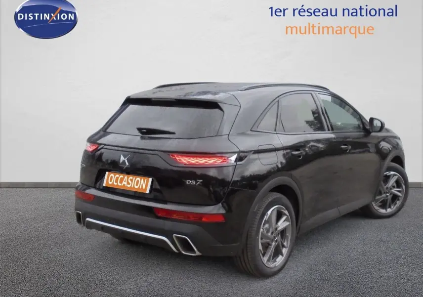 Vue 3/4 arrière droite du DS7 Crossback E-TENSE noir perle métal avec feux allumés et double sortie d'échappement intégrée.