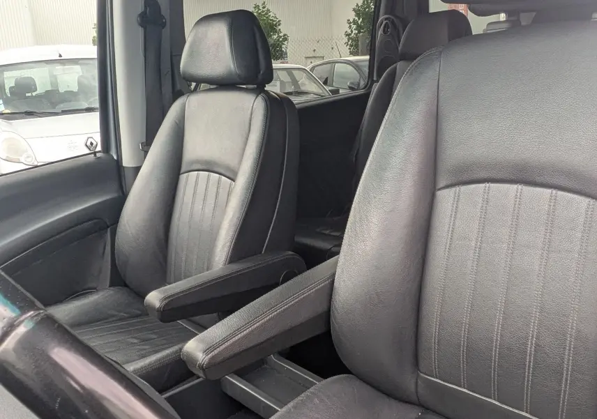 Intérieur du Mercedes Viano 3.0 CDI gris, vue sur les sièges avant en cuir noir avec accoudoirs et volant partiel.