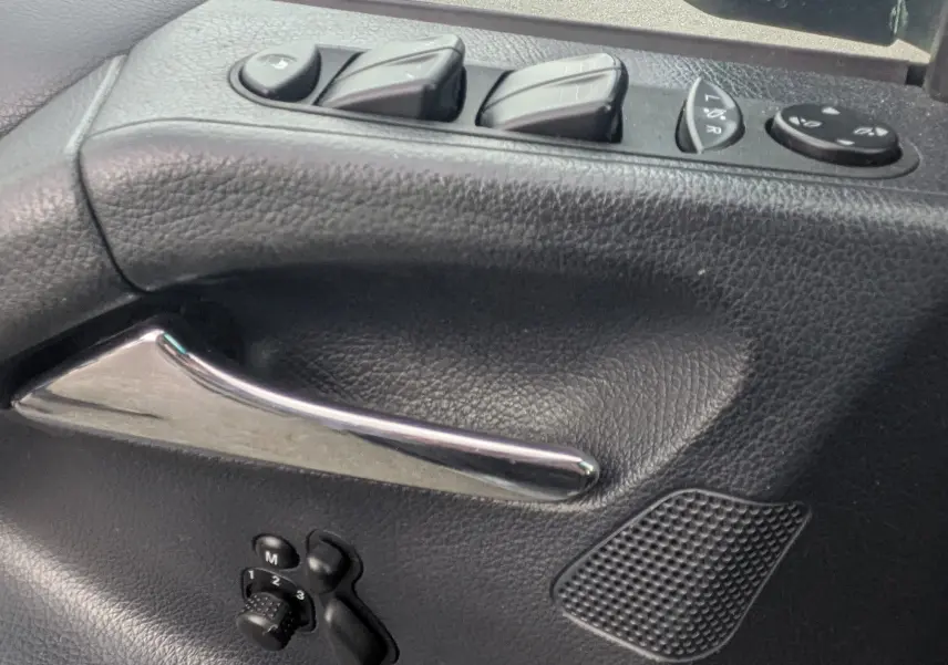 Détail intérieur de la porte conducteur d'un Mercedes Viano 2012 avec commandes électriques et poignée chromée.