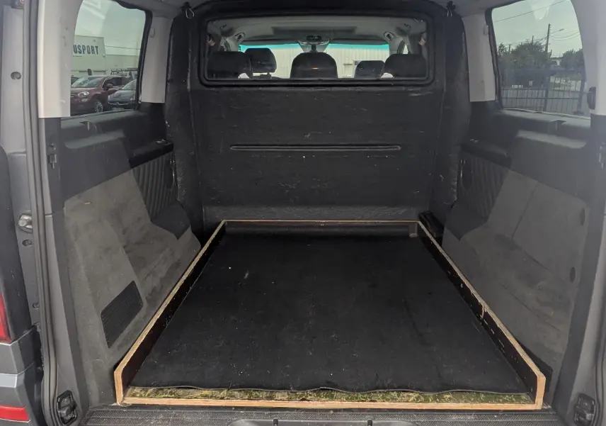 Vue arrière ouverte du Mercedes Viano gris montrant l'espace de chargement vide avec plancher surélevé et habillage intérieur sombre.