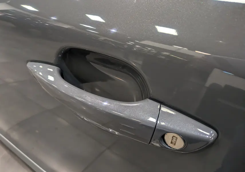 Poignée de porte gris Sélénium du côté gauche d'un Peugeot 2008 Hybrid 145 e-DCS6 Allure 2025.