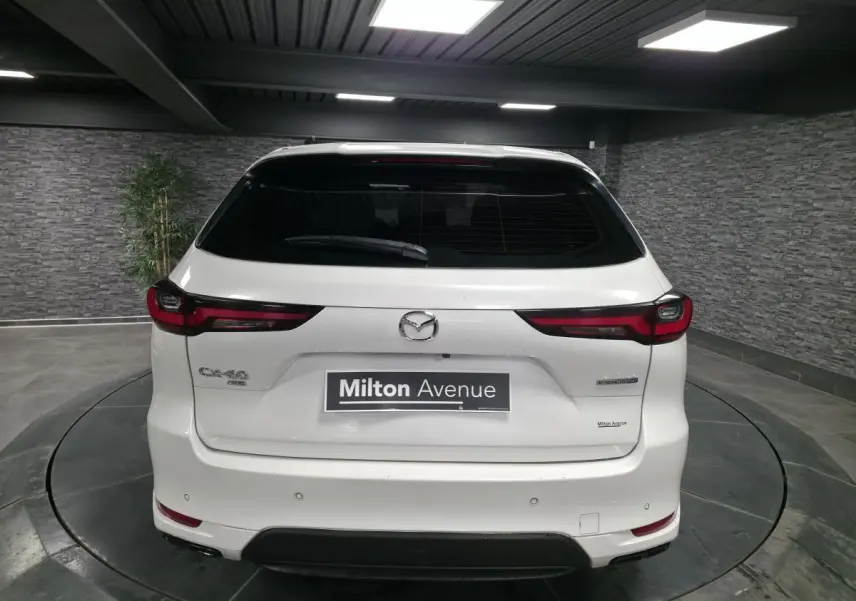 Vue arrière d'un Mazda CX-60 blanc 2023 hybride rechargeable avec feux arrière LED et logo central visible.