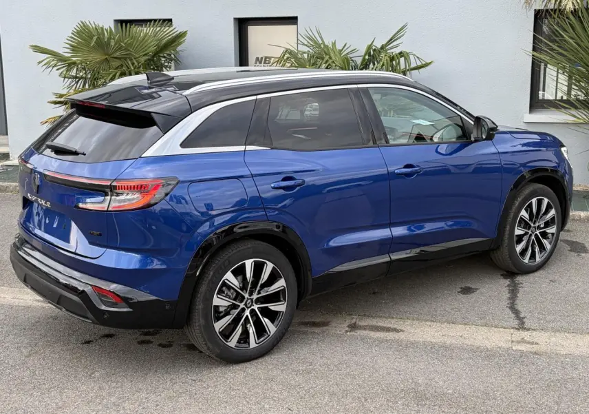 Vue 3/4 arrière droite du Renault Austral 2025 bleu Iron avec toit noir et jantes alliage noires diamantées.