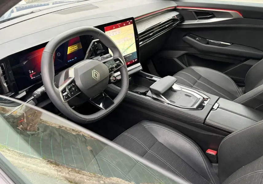 Vue intérieure côté conducteur du Renault Austral 2025, avec volant compact, écran tactile vertical et sellerie mixte noire.