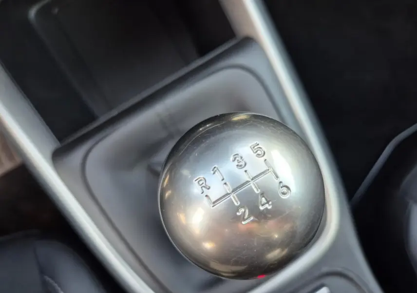 Gros plan sur le levier de vitesses manuel argenté du Jeep Avenger noir, version 2024, avec console grise en arrière-plan.