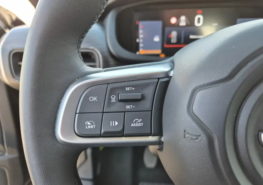 Gros plan sur les commandes au volant côté gauche du Jeep Avenger noir 2024, avec affichage numérique en arrière-plan.