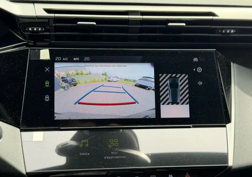 Vue rapprochée de l'écran tactile intérieur affichant la caméra de recul et l'aide au stationnement du Peugeot 308 gris Artense.