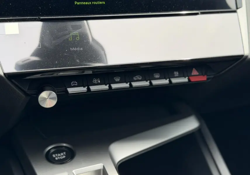 Vue rapprochée de la console centrale de la Peugeot 308 gris Artense, avec boutons de commande et bouton start/stop visible.