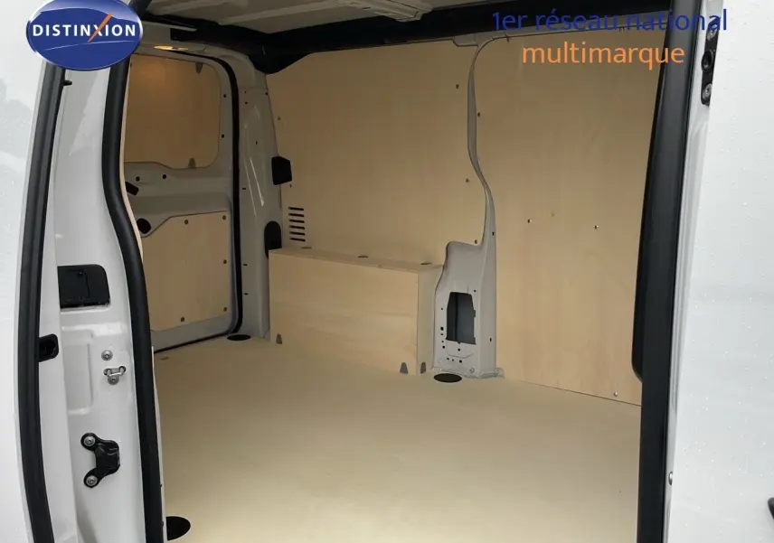 Intérieur du fourgon Peugeot Expert blanc vu côté gauche, montrant l'espace de chargement avec parois en bois clair.