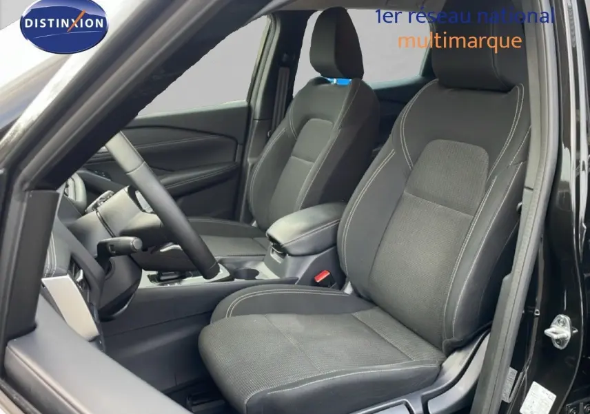 Vue intérieure côté conducteur du Nissan Qashqai 2023 noir métal, mettant en valeur les sièges tissu avec surpiqûres contrastées.