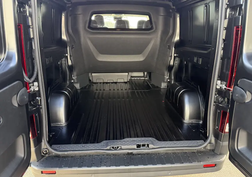 Vue arrière ouverte du Renault Trafic cabine approfondie noir, montrant l'espace de chargement vide et les portes battantes ouvertes.