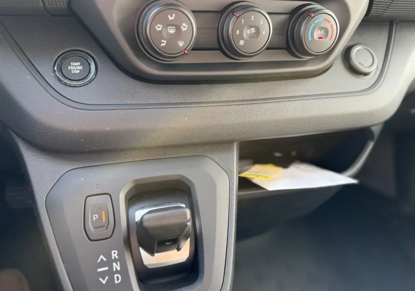 Gros plan sur la console centrale du Renault Trafic cabine approfondie 2025, boîte auto et commandes climatisation visibles.