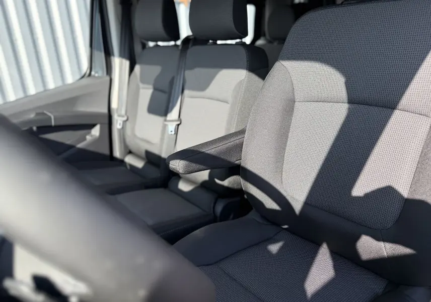 Vue rapprochée des sièges avant en tissu gris du Renault Trafic Cabine Approfondie noir, avec accoudoir côté droit visible.
