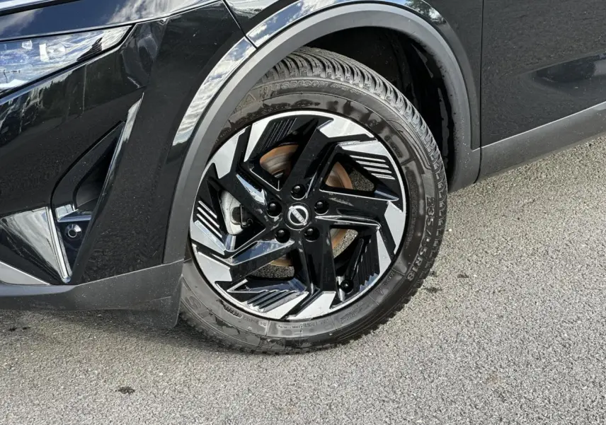 Gros plan sur la roue avant gauche du Nissan Qashqai noir nacré avec jante alliage 18 pouces au design moderne.