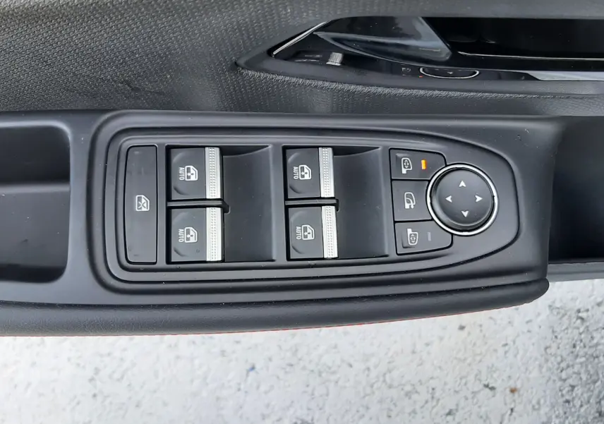 Vue rapprochée du panneau de commandes des vitres et rétroviseurs côté gauche d’une Renault Clio VI gris Rafale.