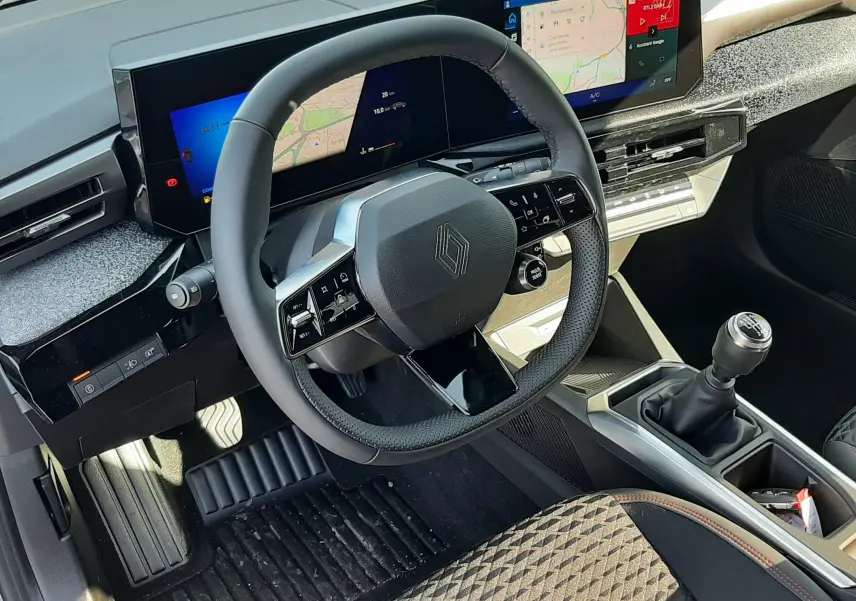 Vue intérieure du poste de conduite de la Renault Clio VI TCe 115ch Techno, volant multifonctions et écran large numérique.