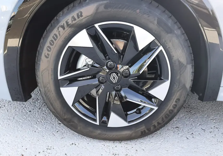 Gros plan sur la roue avant droite d’une Renault Clio VI gris Rafale, jante alliage noire et argentée au design géométrique.