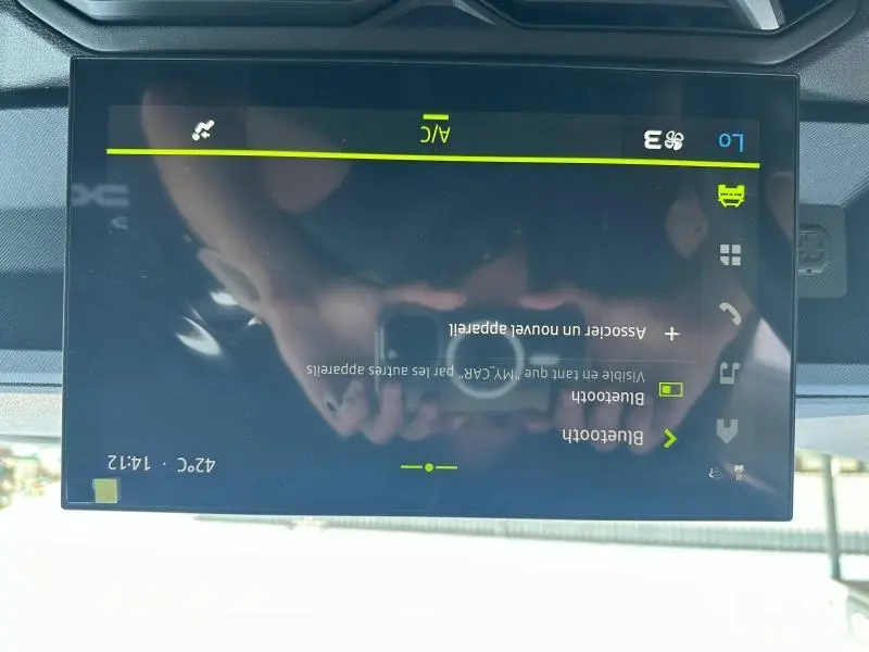 Écran tactile central affichant les réglages Bluetooth du Dacia Duster blanc, vue rapprochée de l'intérieur.