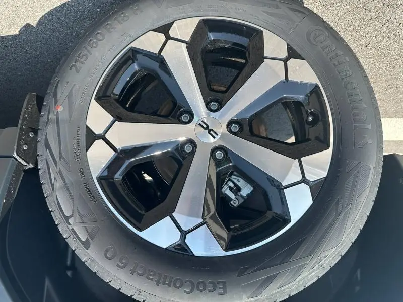 Gros plan sur la jante alliage noire et argentée du Dacia Duster blanc 2025, avec pneu Continental visible.
