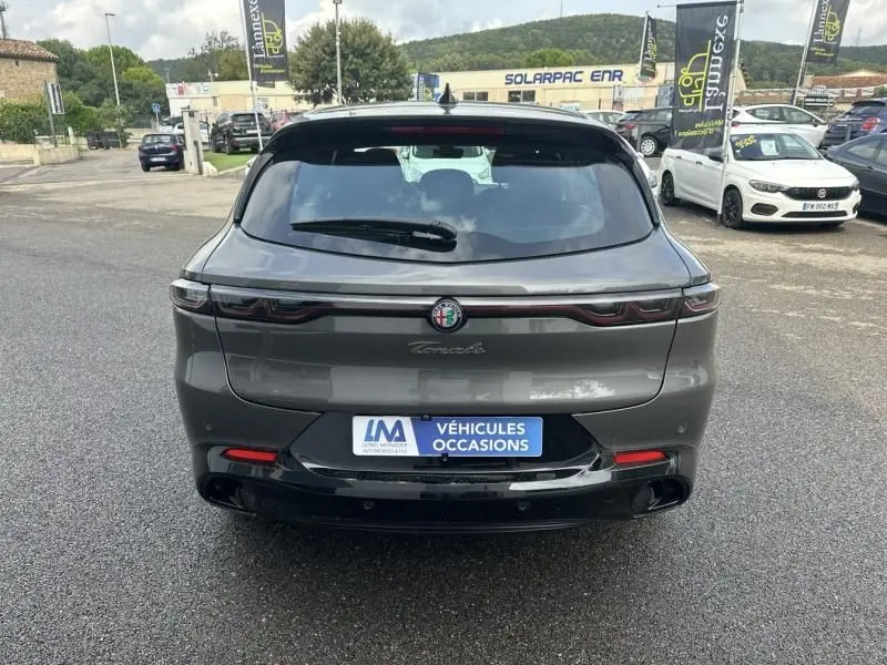 Vue arrière d'une Alfa Romeo Tonale 1.5 Hybrid Sprint 2024 en gris foncé métal avec feux reliés par un bandeau lumineux.