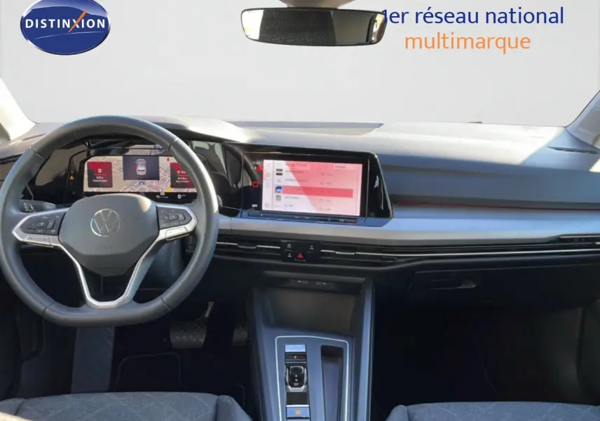 Intérieur de la Volkswagen Golf VIII rouge roi métal, vue frontale sur le tableau de bord et volant multifonction.