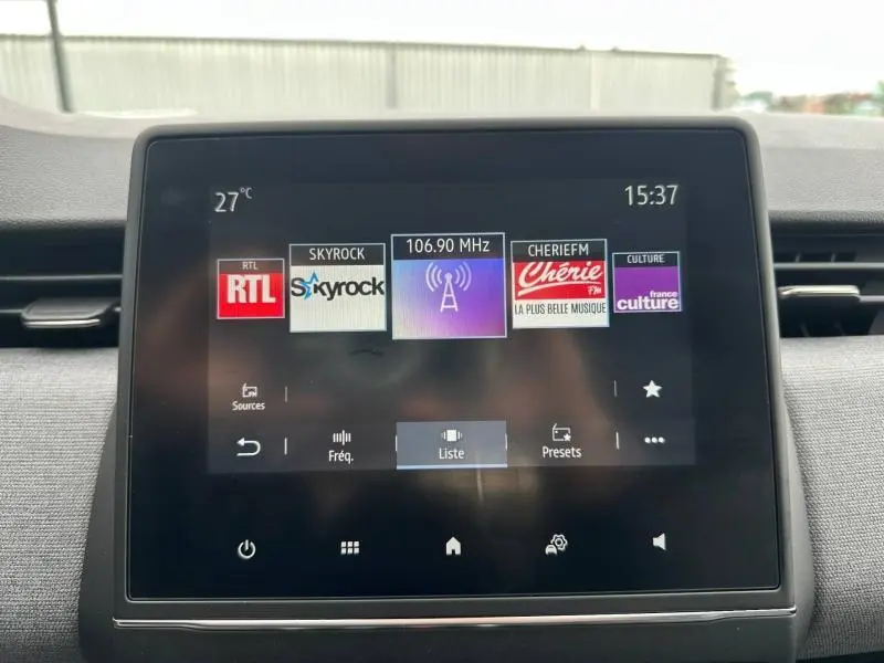 Écran tactile central de la Renault Clio 2025 affichant les stations radio avec interface moderne et fond noir.