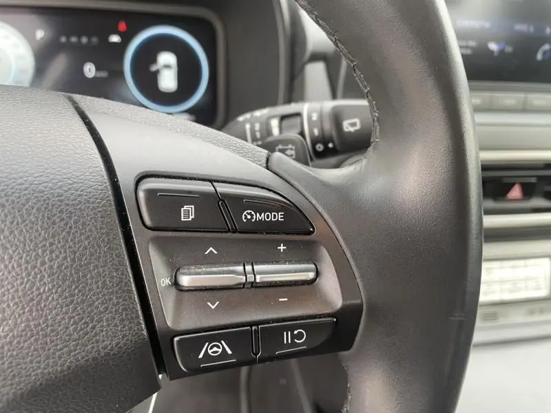 Gros plan sur les commandes au volant du Hyundai Kona électrique 2021, boutons de mode et régulateur de vitesse visibles.