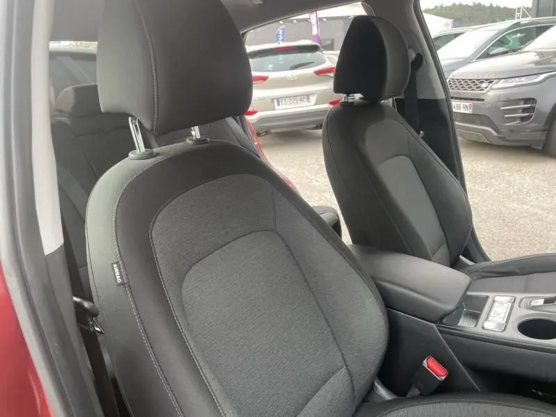 Vue intérieure des sièges avant noirs du Hyundai Kona électrique rouge métal 2021, avec console centrale visible.