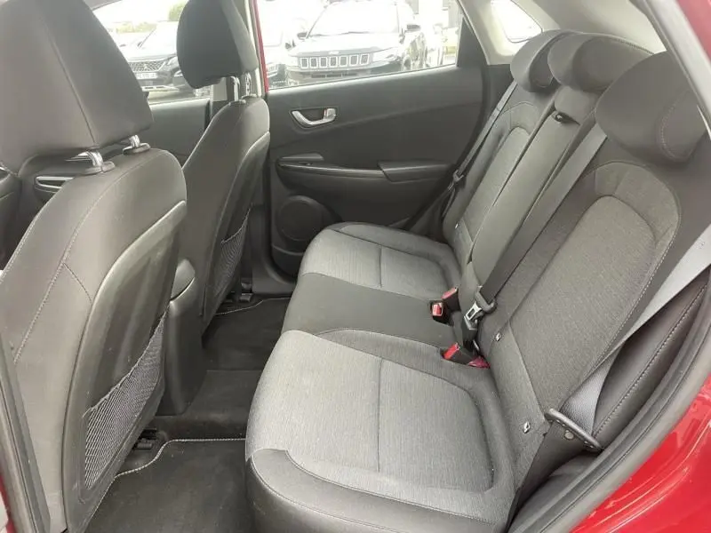 Vue intérieure côté arrière droit du Hyundai Kona électrique rouge métal 2021, montrant les sièges arrière en tissu gris.