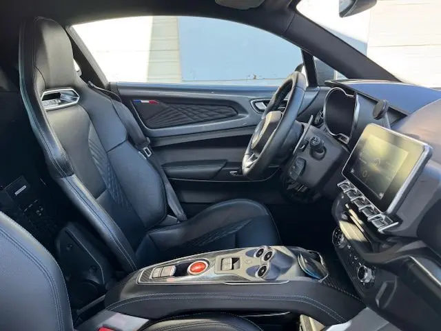 Intérieur de l'Alpine A110 1.8T 252 Légende 2021, vue côté conducteur, cuir noir surpiqué bleu et console carbone brillant.