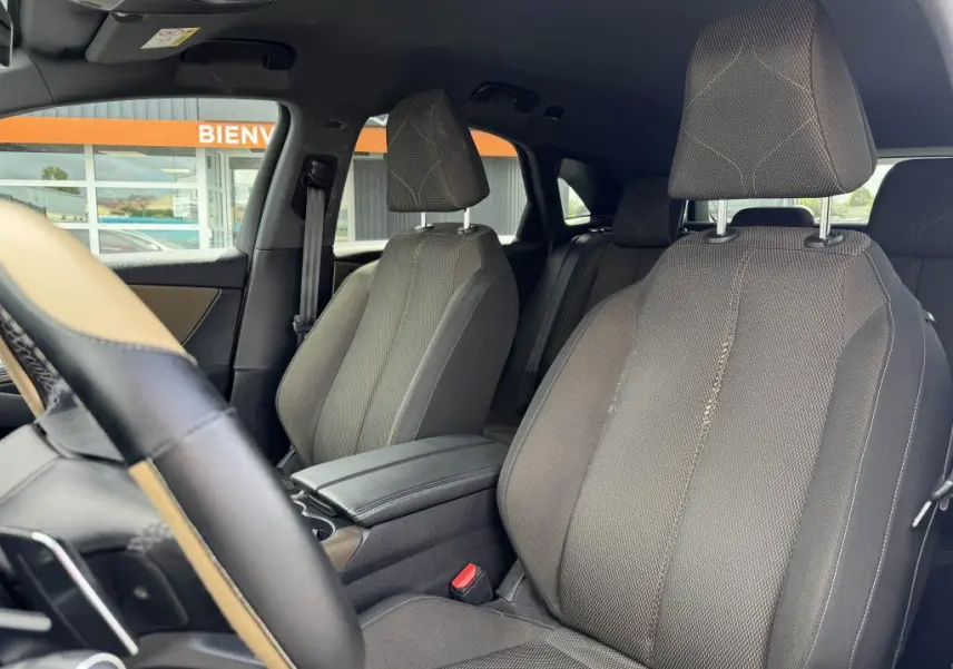 Vue intérieure sur les sièges avant en tissu bronze du DS7 Crossback gris, avec accoudoir central et volant partiel visible.