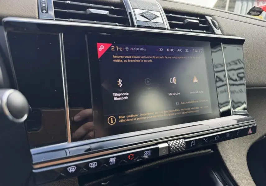 Vue rapprochée de l'écran tactile central noir brillant du tableau de bord du DS7 Crossback 2022 avec commandes climatisation.