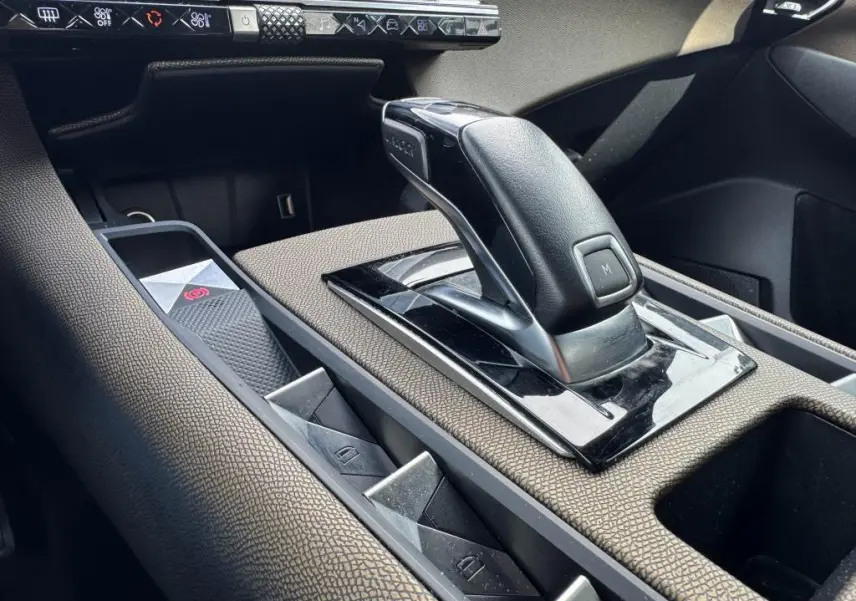 Le levier de vitesse automatique noir et cuir du DS7 Crossback 2022, entouré de console en tissu bronze et commandes électriques.