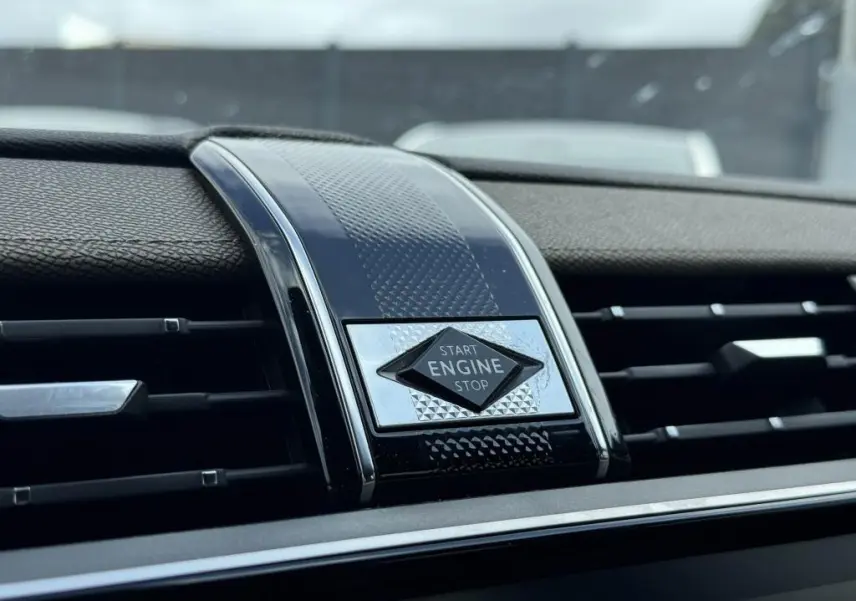 Gros plan sur le bouton Start Engine Stop entouré de décor noir et chrome dans le tableau de bord du DS7 Crossback gris.