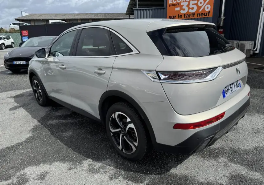 DS7 Crossback gris métallisé vu en 3/4 arrière côté gauche, avec feux arrière 3D et vitres teintées.