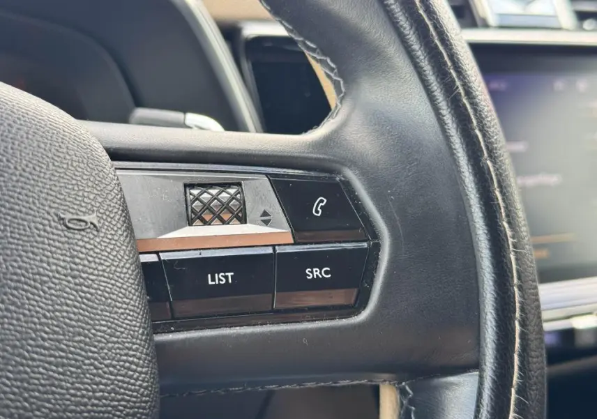 Gros plan sur les commandes gauche du volant cuir noir du DS7 Crossback 2022 avec touches LIST et SRC.