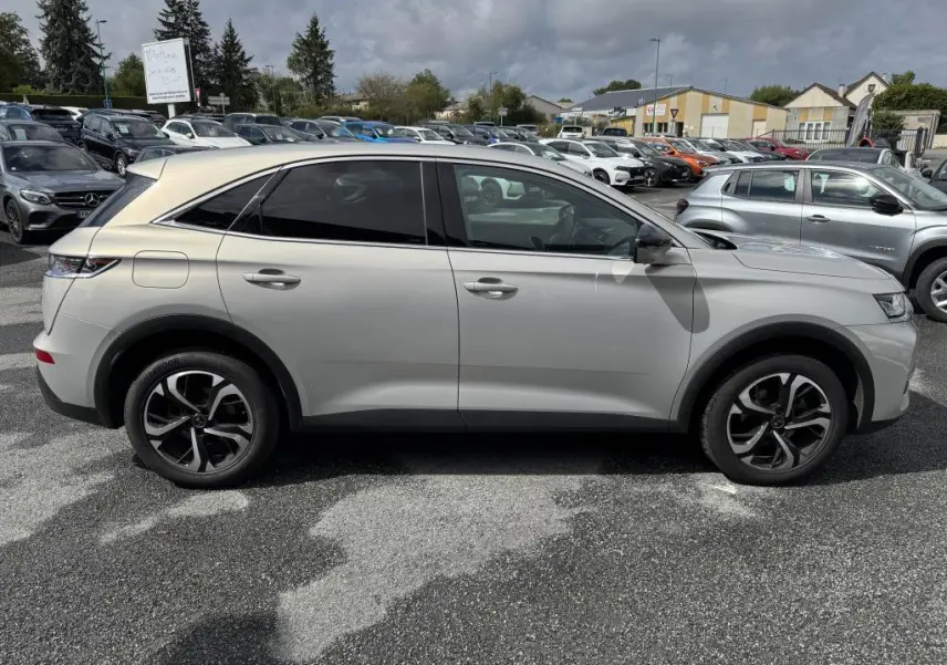 Profil droit d'un DS7 Crossback gris métallisé avec jantes alliage 18 pouces, garé en extérieur sur un parking.