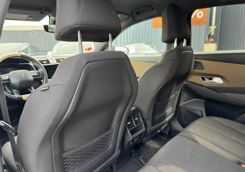 Vue intérieure arrière du DS7 Crossback gris, montrant les sièges avant en tissu noir et les aérateurs centraux.